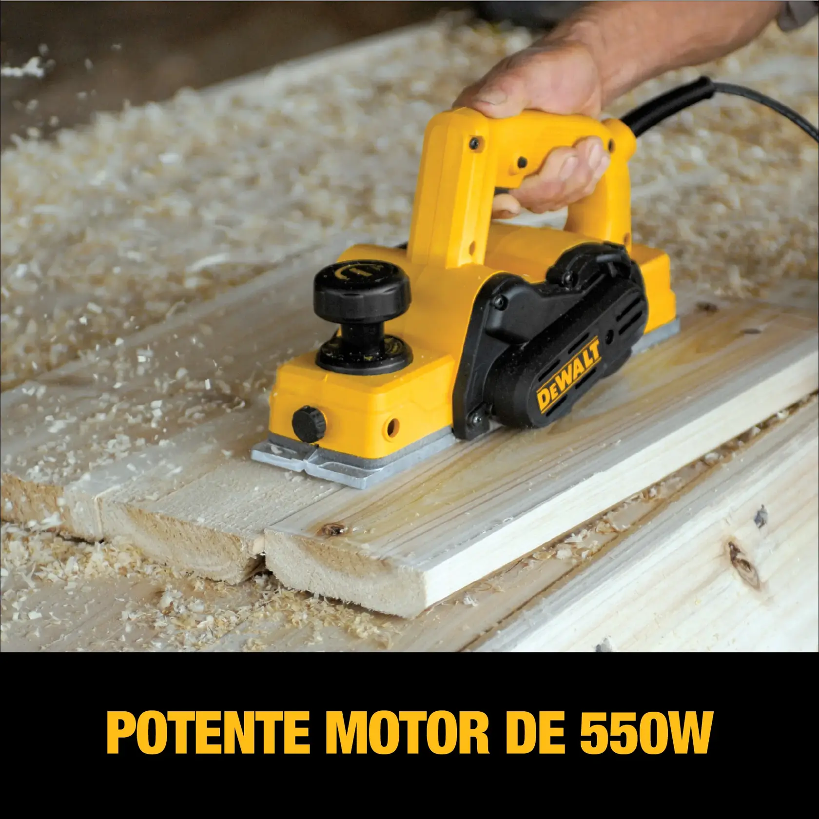 Una persona utiliza una cepilladora eléctrica amarilla DEWALT para alisar tablas de madera, con virutas de madera esparcidas alrededor. La imagen resalta el potente motor de 550W de la herramienta.