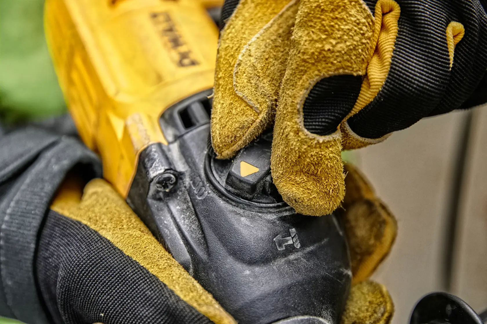 Primer plano de una mano enguantada ajustando el selector de modo en una herramienta eléctrica amarilla DEWALT.