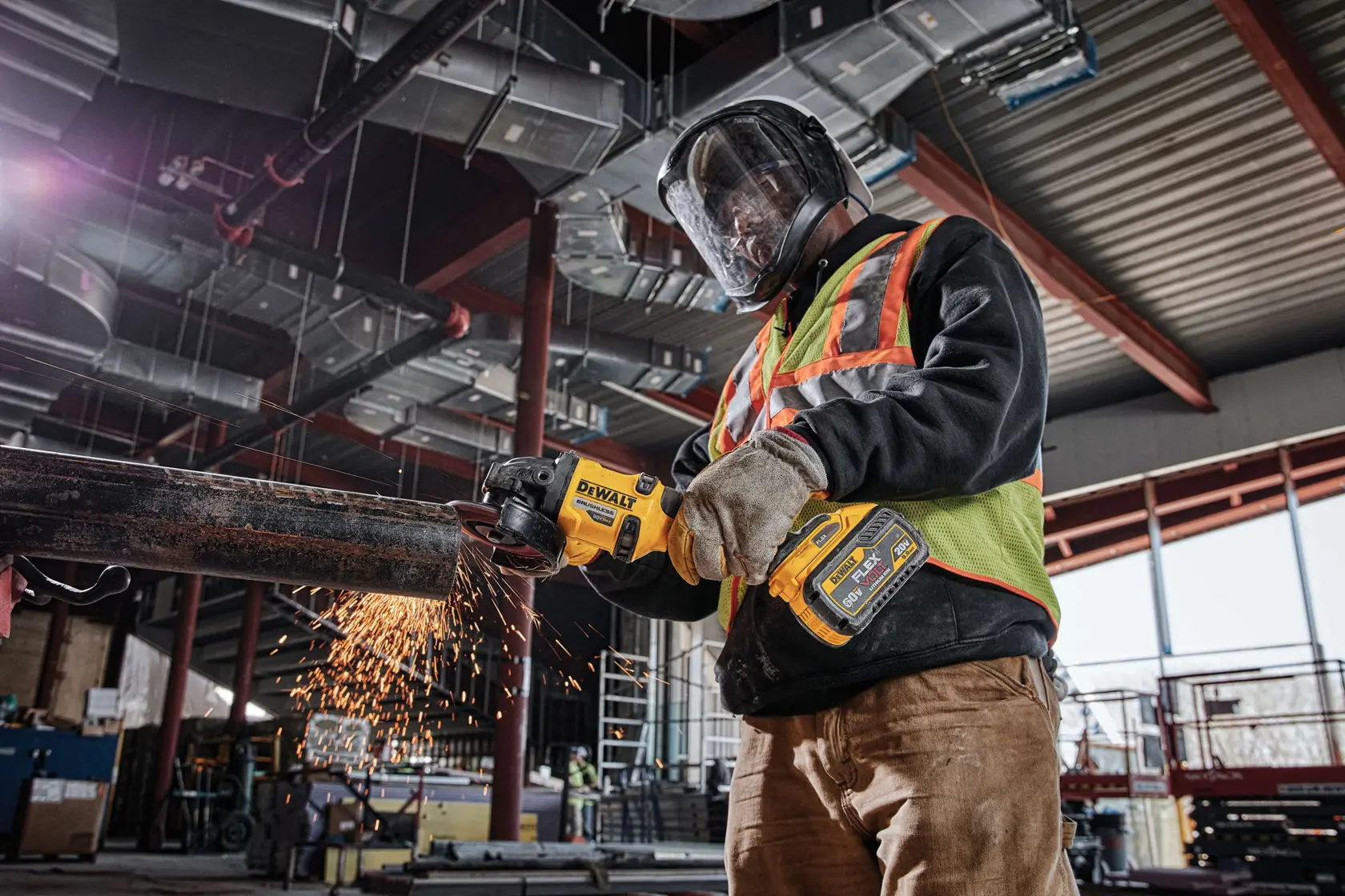 Trabajador corta tubo de metal con herramienta DEWALT DCB609 en obra, usando equipo de protección.