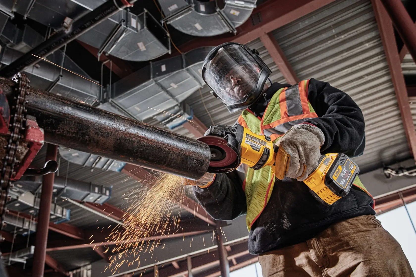 Trabajador usa una amoladora DEWALT inalámbrica en un tubo metálico, con protección. Salen chispas.