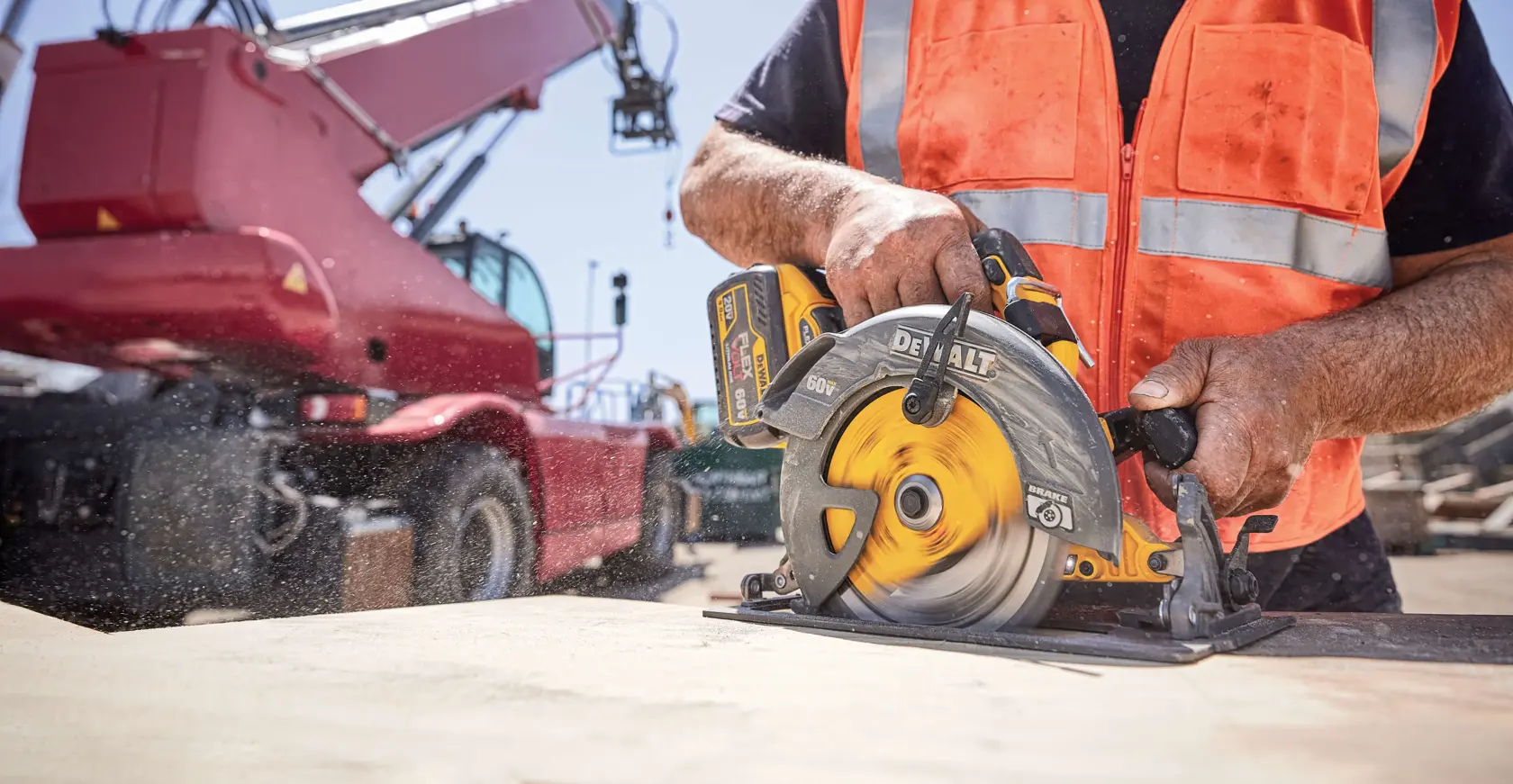 Trabajador corta madera con sierra circular DEWALT en una obra, usando chaleco de seguridad naranja.