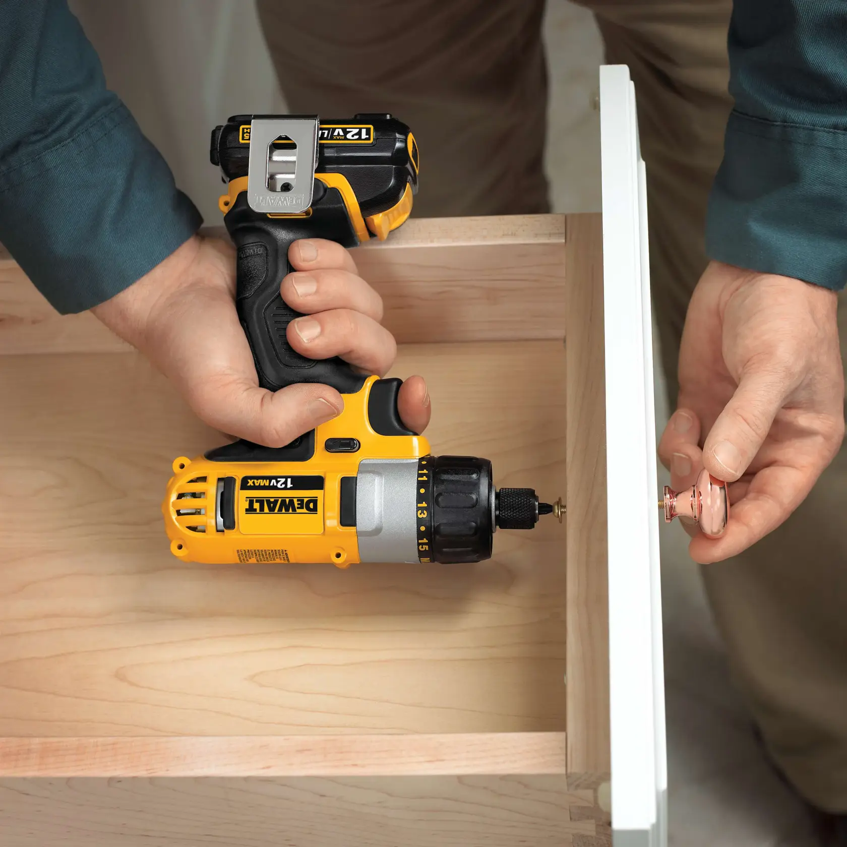 Una persona utiliza un taladro inalámbrico DEWALT 12V Max para instalar un tirador en un cajón de madera.