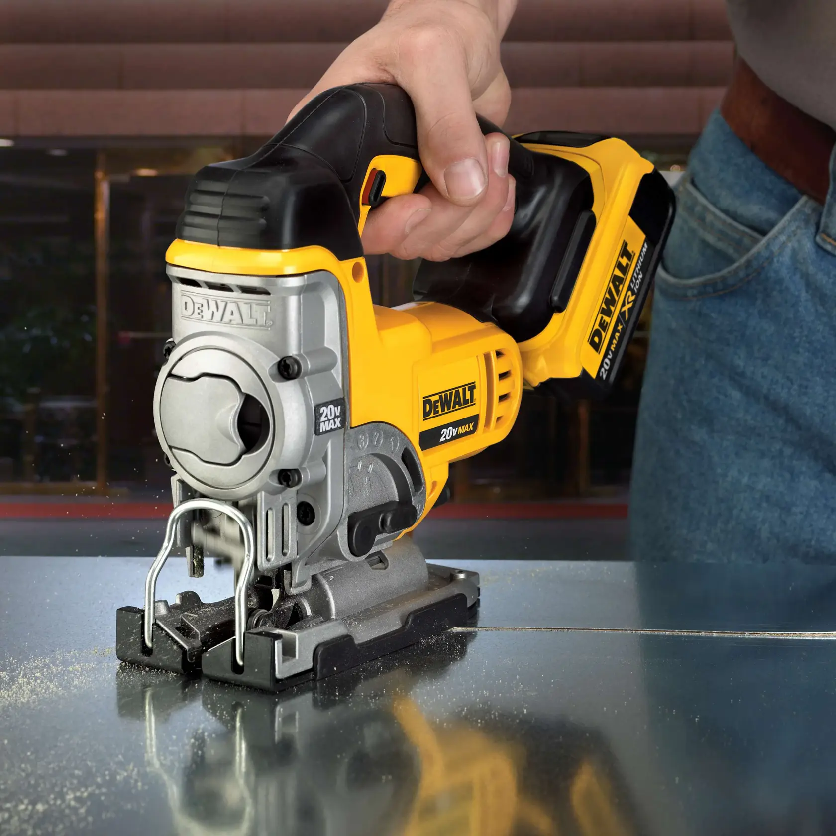 Primer plano de una persona usando una sierra de calar inalámbrica DEWALT 20V Max para cortar una hoja de metal.