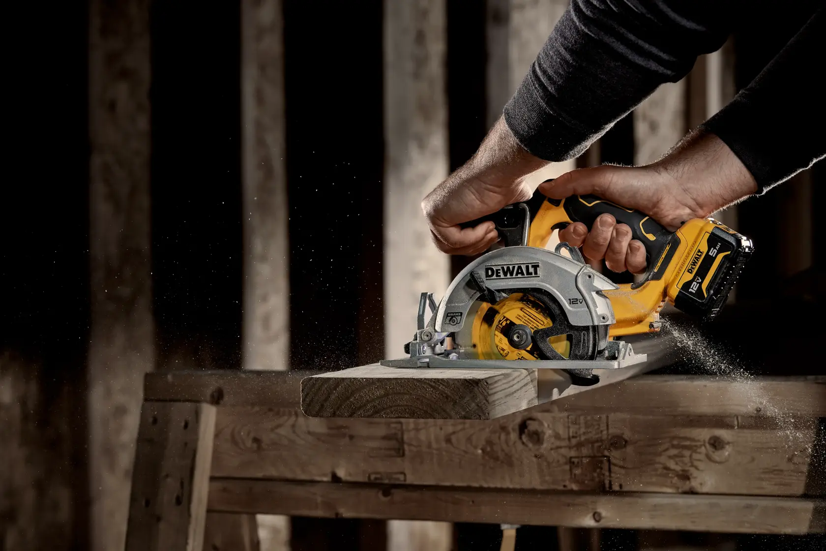 Una persona utiliza una sierra circular inalámbrica DEWALT para cortar un trozo de madera en un banco de trabajo, con aserrín volando.