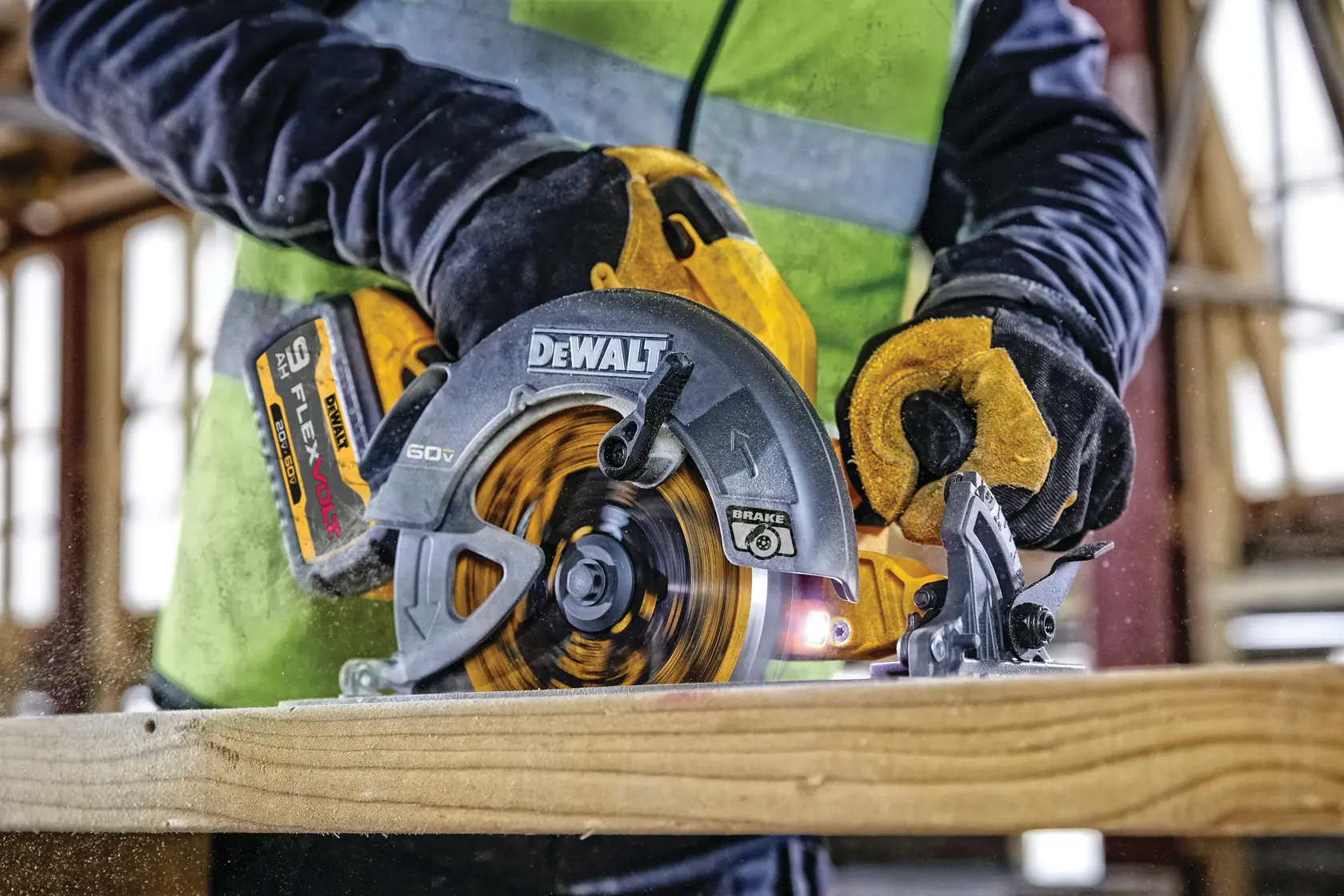 Vista de cerca de una persona usando una sierra circular DEWALT DCS578X2 60V con batería FLEXVOLT para cortar una tabla de madera. La persona lleva guantes de seguridad y un chaleco de alta visibilidad.