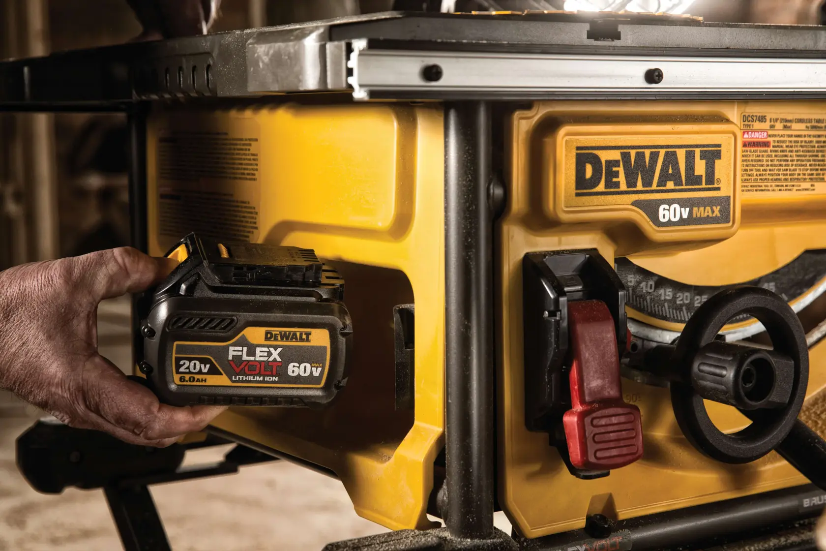 Vista de cerca de una sierra de mesa DEWALT 60V MAX con una mano insertando una batería de ion de litio FLEXVOLT 20V/60V en la máquina. La marca de DEWALT en amarillo y negro es visible en la batería y en el cuerpo de la sierra de mesa.