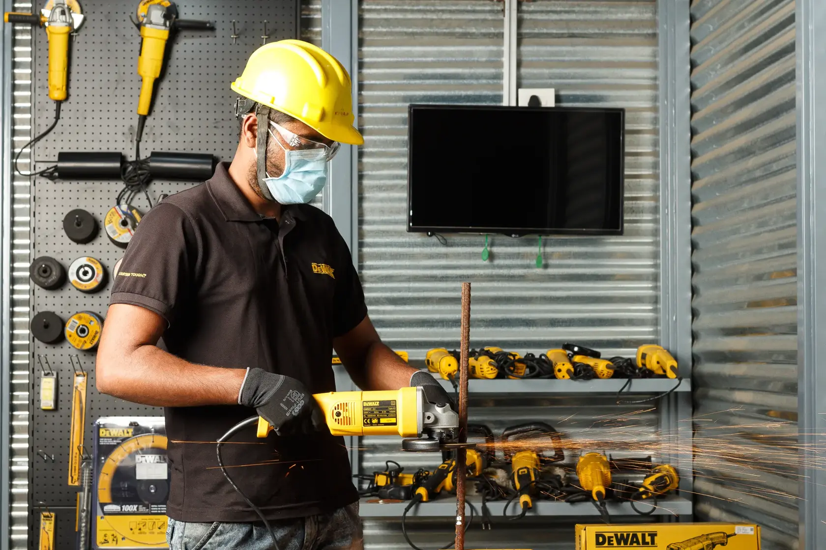 Trabajador usa DEWALT DW831 amoladora en barra de metal en taller, herramientas visibles atrás.