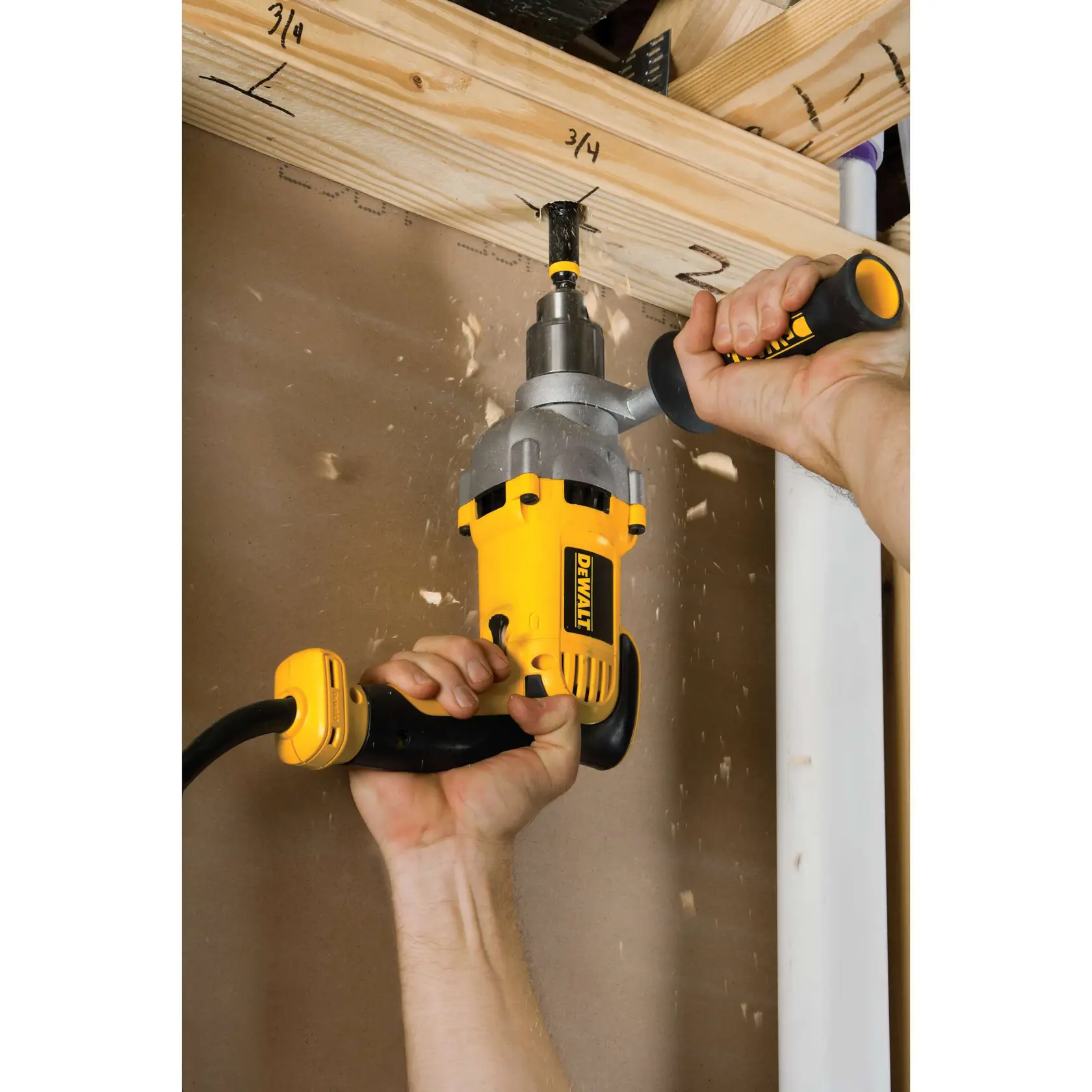 Un taladro eléctrico DEWALT siendo utilizado por una persona para perforar un agujero en una viga de madera, con virutas de madera volando alrededor.