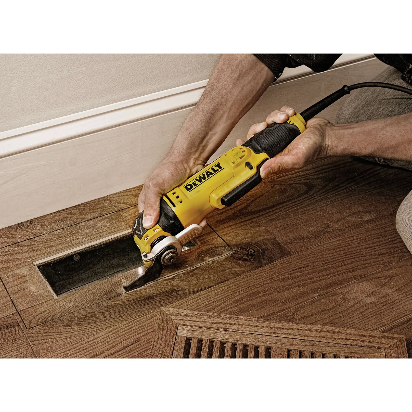 Una persona utiliza una herramienta multifunción oscilante DEWALT DWE315 para cortar un panel de suelo de madera cerca de una pared.