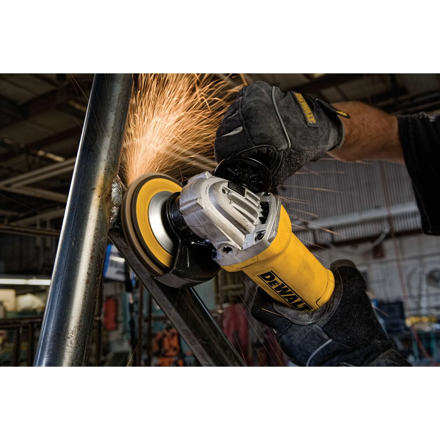 Imagen en primer plano de una amoladora angular DEWALT siendo utilizada en una tubería de metal, con chispas volando mientras la herramienta pule la superficie. La persona que maneja la herramienta lleva guantes protectores y la escena ocurre en un taller industrial.