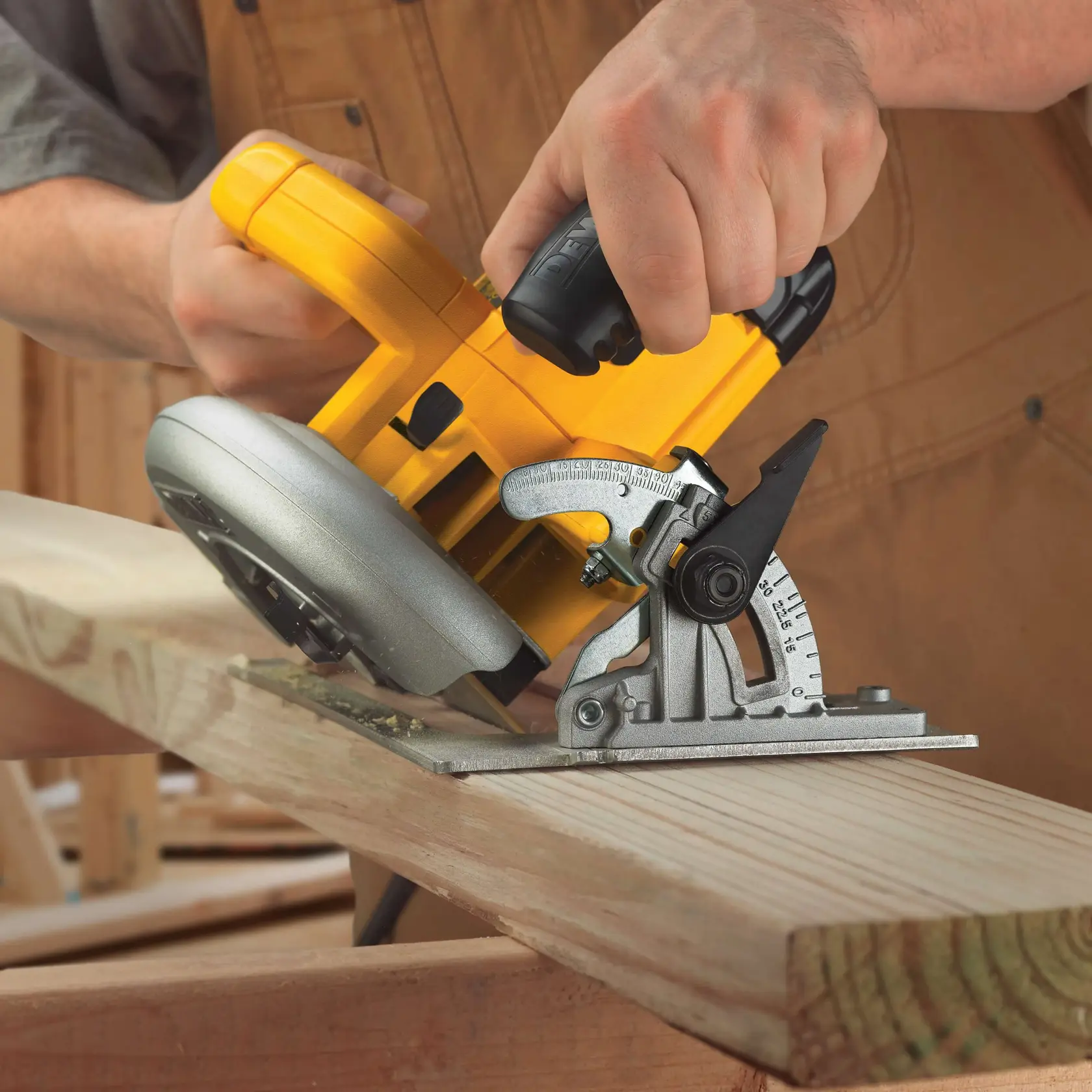 Una persona utiliza una sierra circular amarilla DEWALT DWE575 para cortar una pieza de madera en ángulo. Se pueden ver la base y el mecanismo de ajuste de ángulo de la sierra, y la persona lleva un delantal de trabajo marrón.