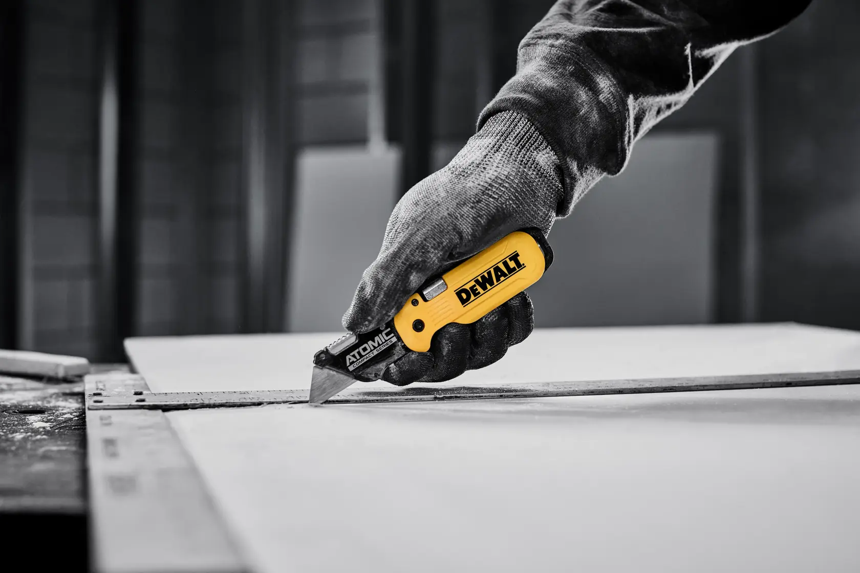 Un cúter de la serie Atomic Compact de DEWALT con mango amarillo y negro y hoja afilada reemplazable.