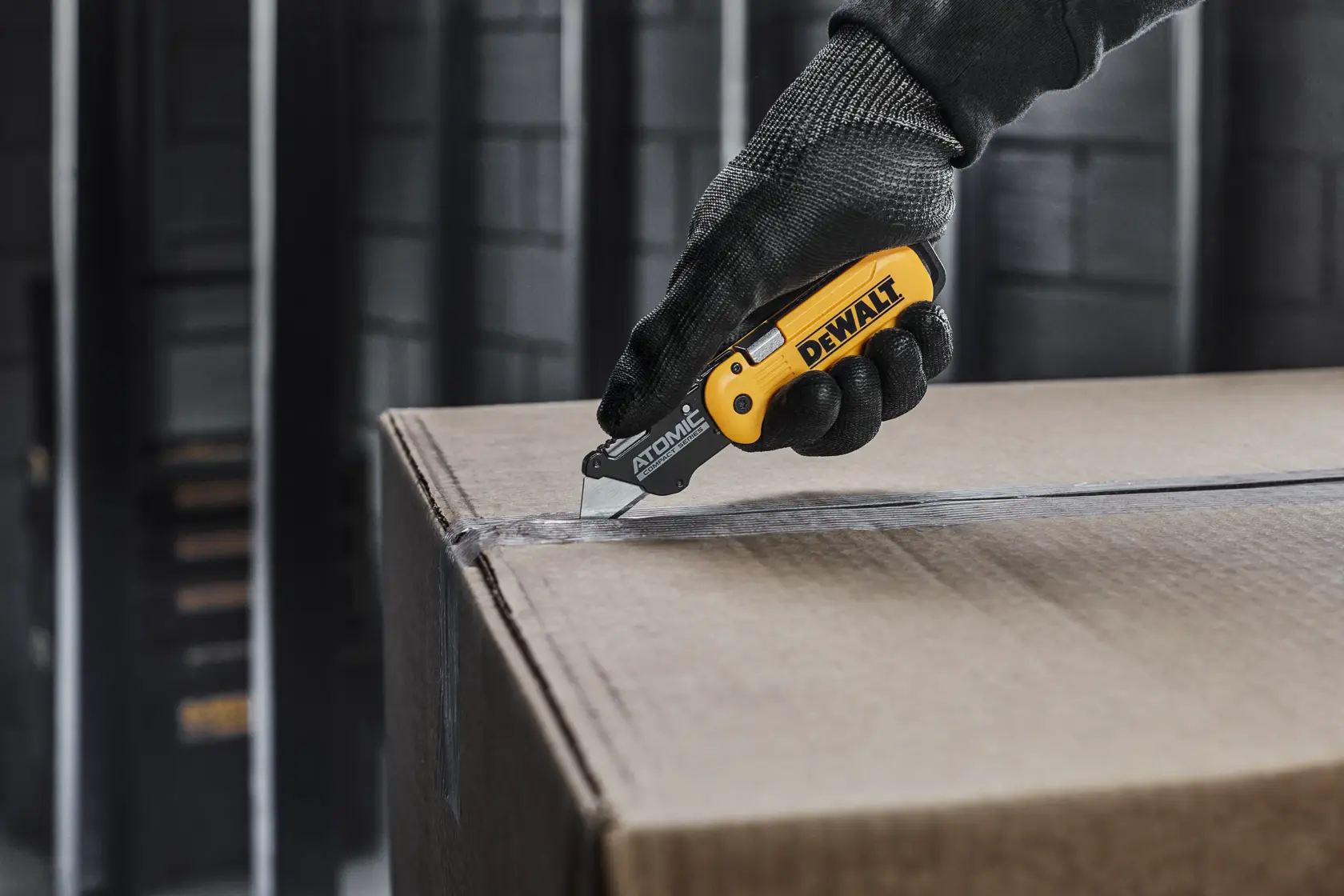 Cuchillo utilitario plegable DEWALT amarillo y negro con clip de metal y hoja retráctil, mostrado en vista lateral sobre fondo blanco.