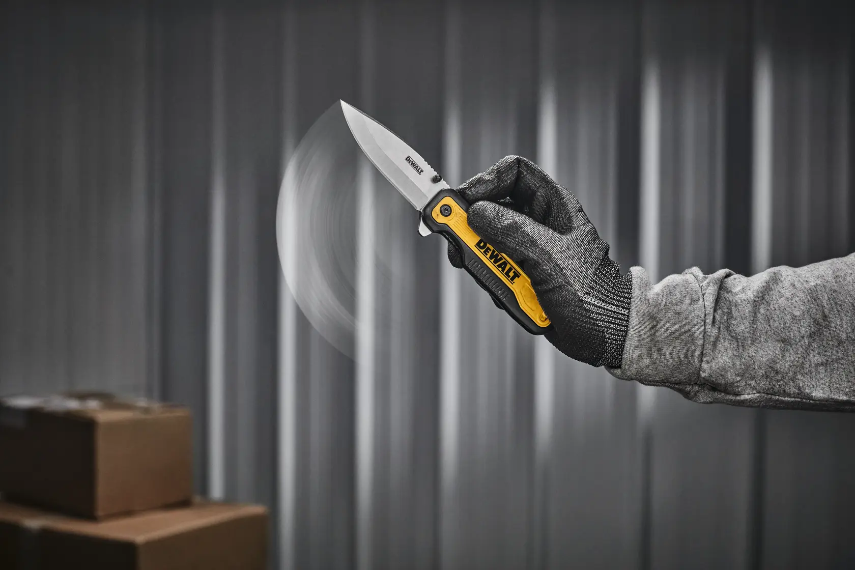 Un cuchillo plegable DEWALT con hoja plateada y mango negro y amarillo, mostrado sobre fondo blanco.