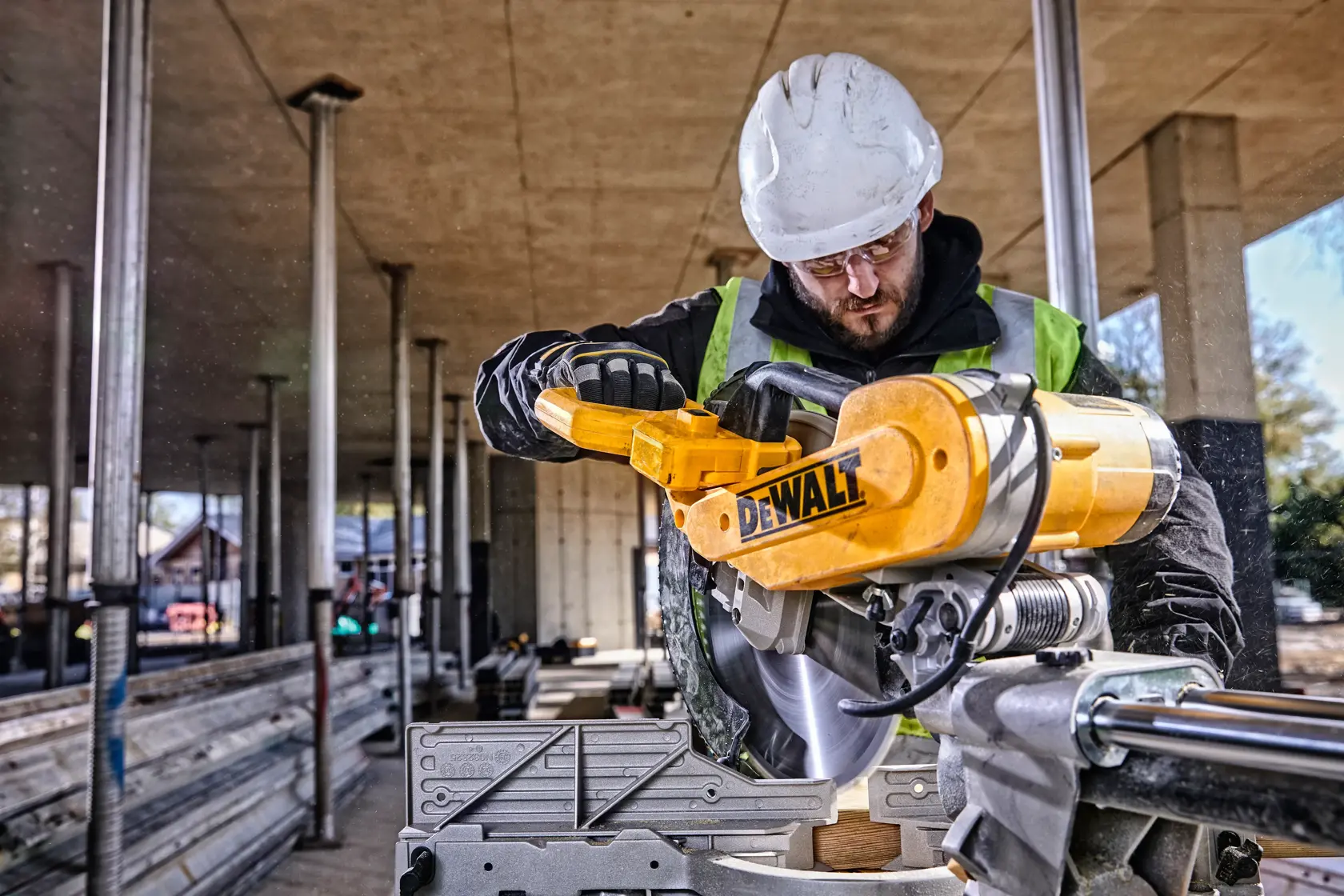 DEWALT DWS780, DWS780KIT sierra usada en obra, trabajador con casco y chaleco. Categoría fotografía.